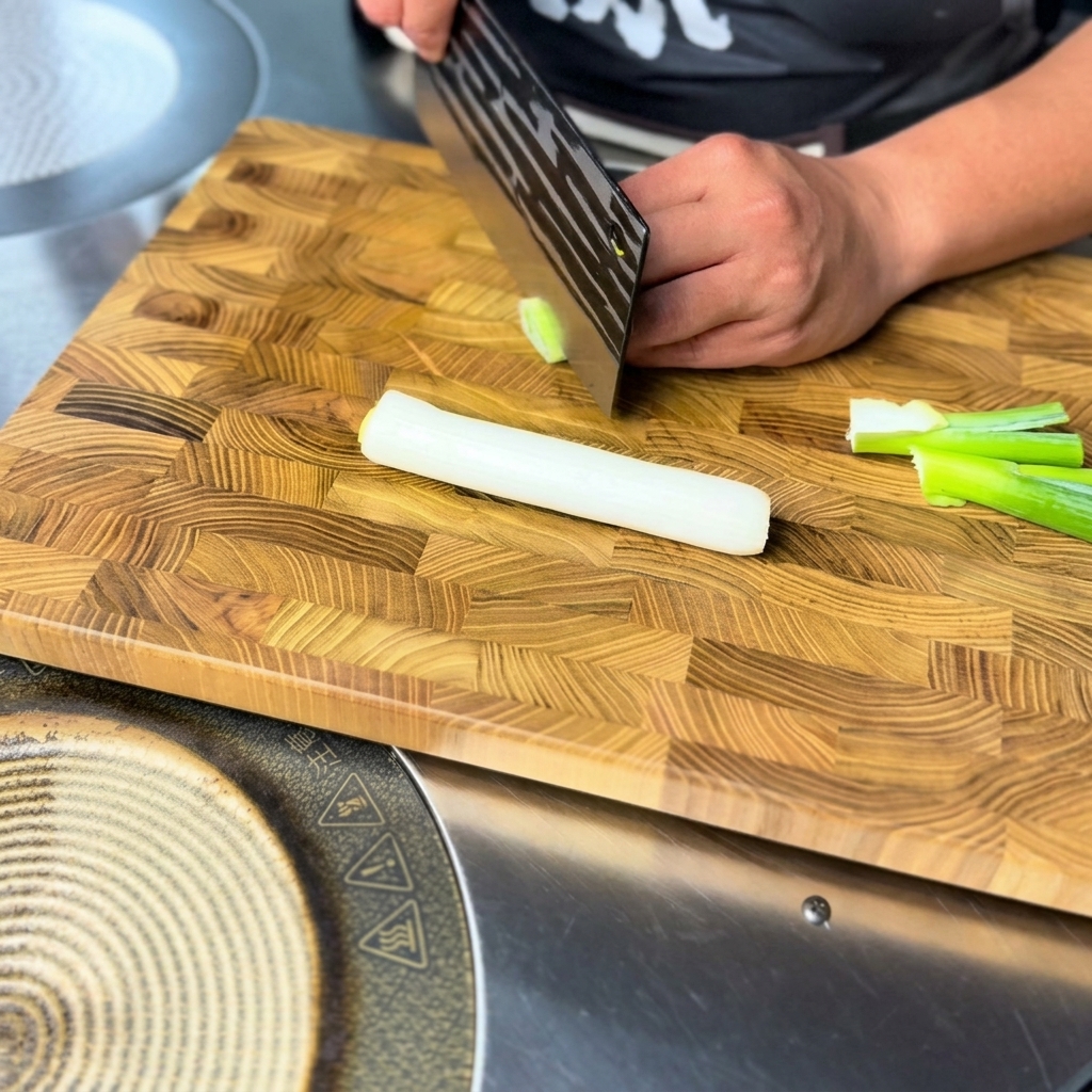 Cipollotto fresco affettato finemente su un tagliere di legno.