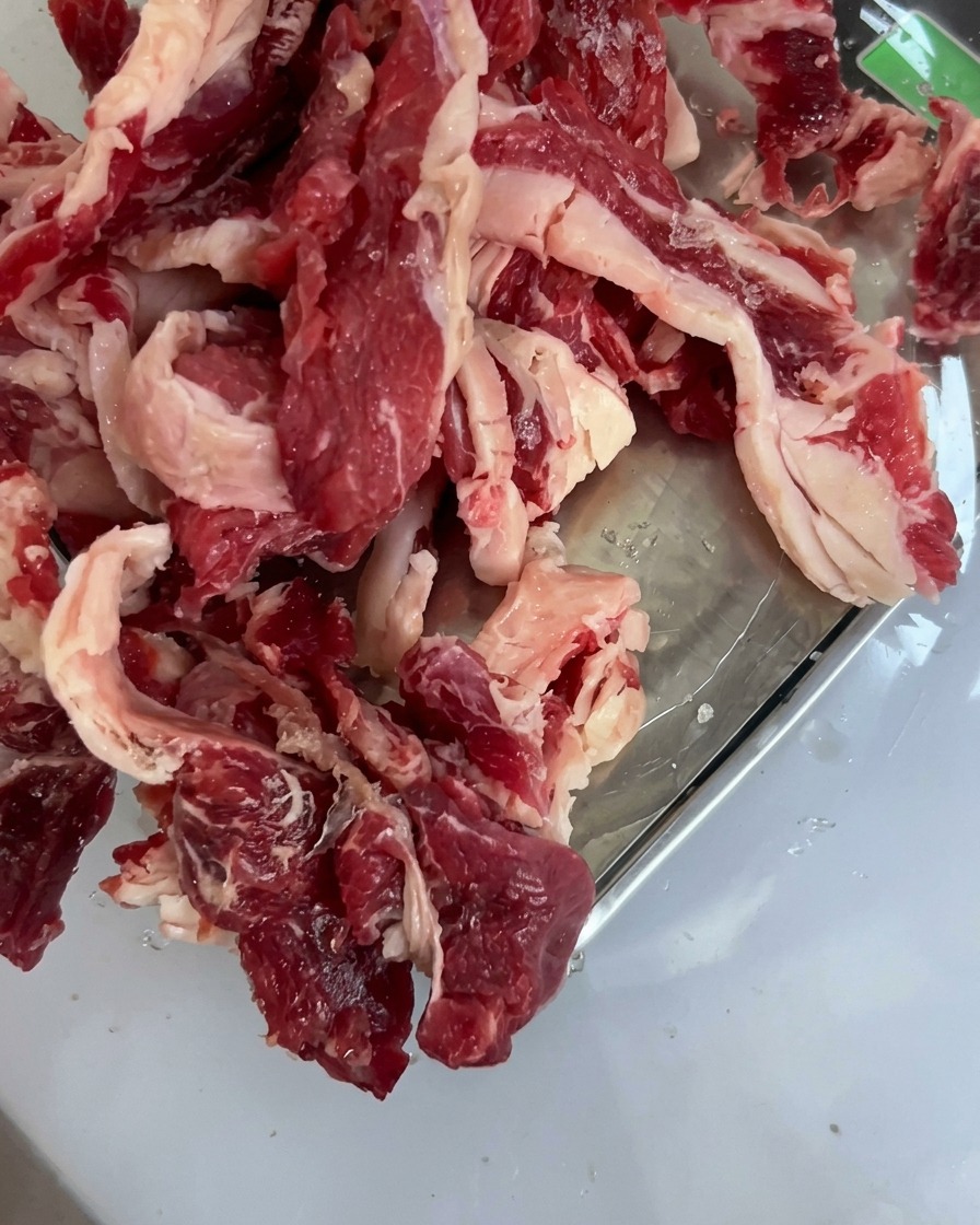 Pezzi di manzo crudo di alta qualità disposti ordinatamente in una teglia di metallo.