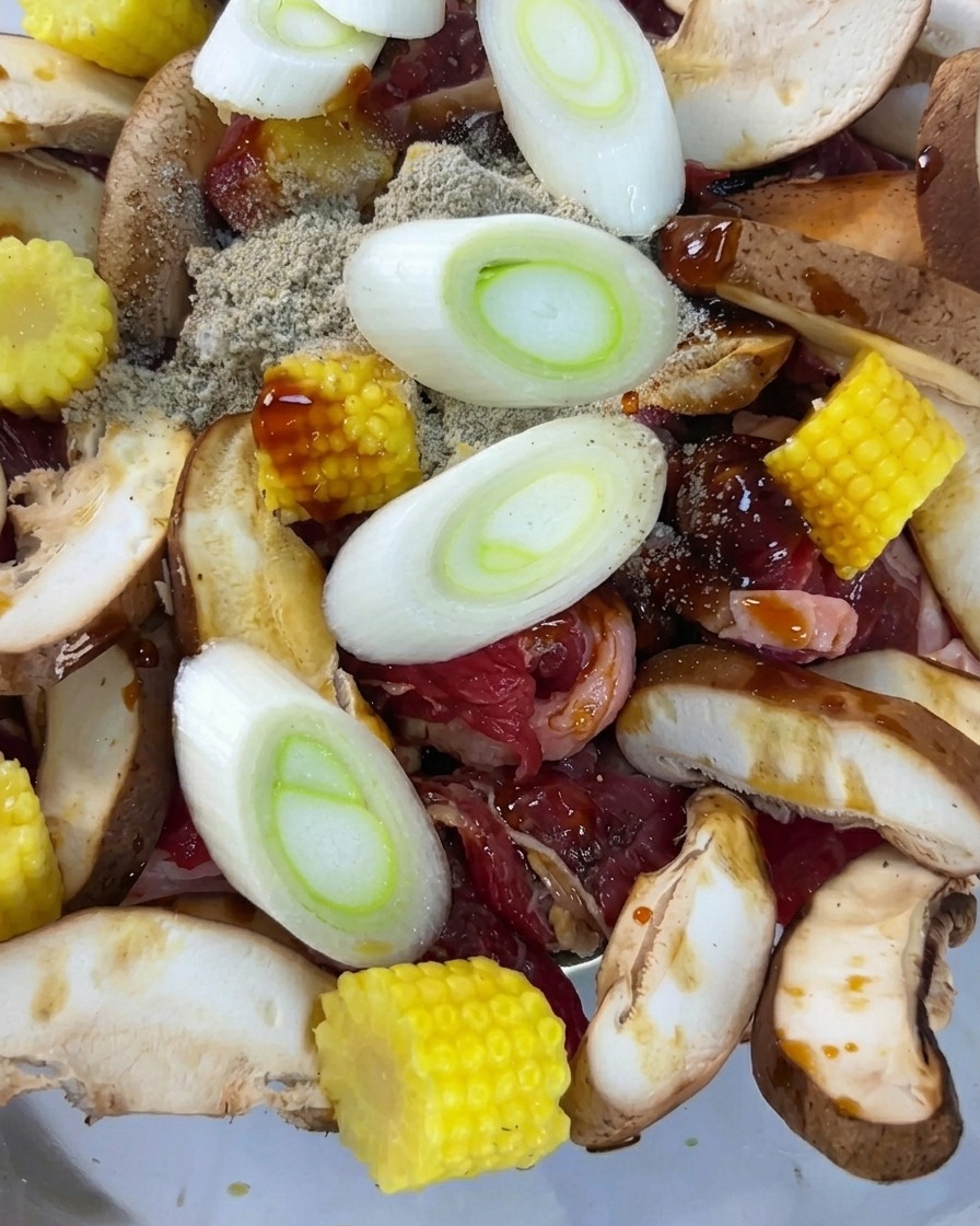 Fettine di cipollotti freschi adagiate sopra la miscela di manzo e verdure condite.