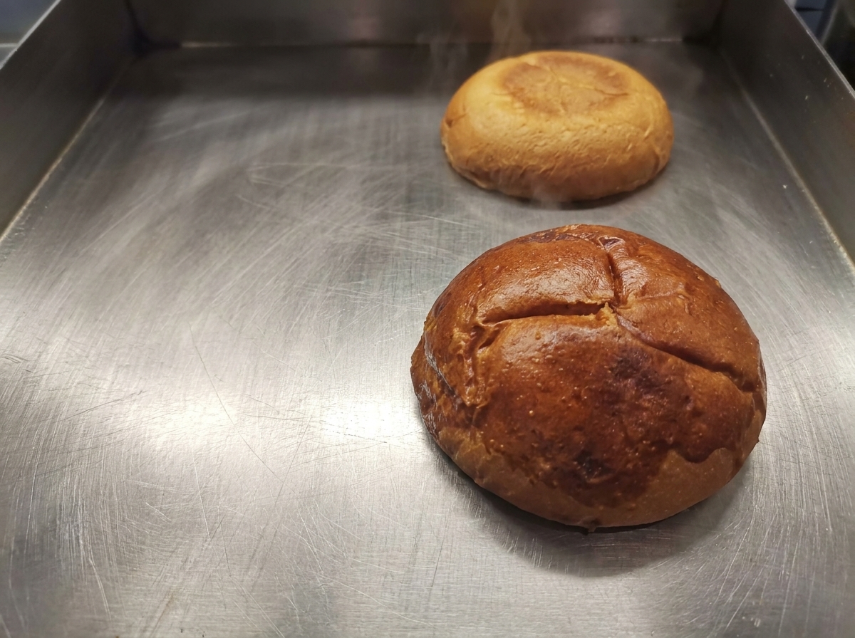 Metà di un panino per hamburger tostato color oro dorato su una piastra pulita.