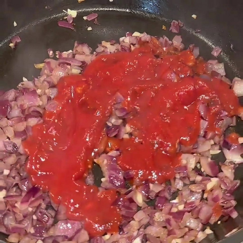 Passata di pomodoro versata in padella con il soffritto di cipolla e aglio.