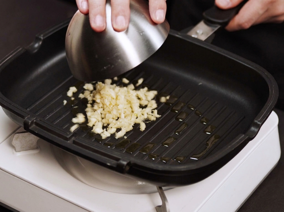 Aglio e cipolla tritati finemente che sfrigolano in una padella calda leggermente unta.