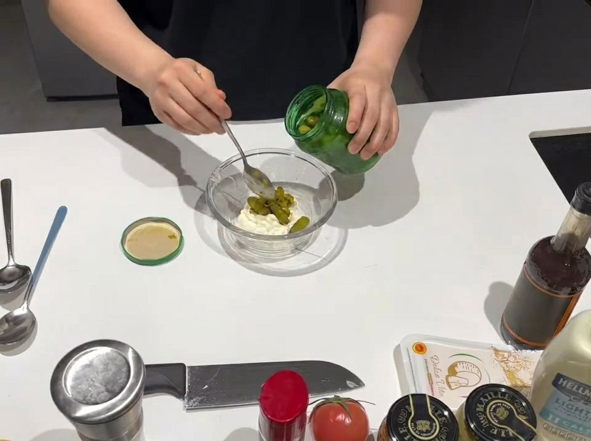 Un cucchiaio di relish dolce aggiunto a una ciotola di maionese cremosa.