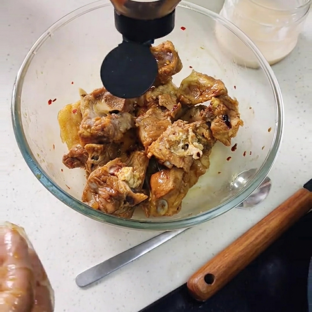 Salsa di ostriche versata nella ciotola sopra le costolette di maiale, con laggiunta di fette di limone.
