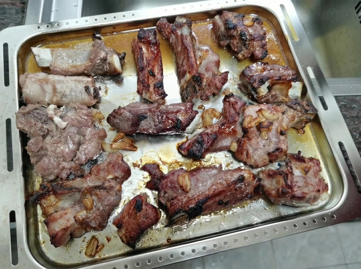 Costine di maiale arrosto e caramellate che riposano su una teglia da forno.