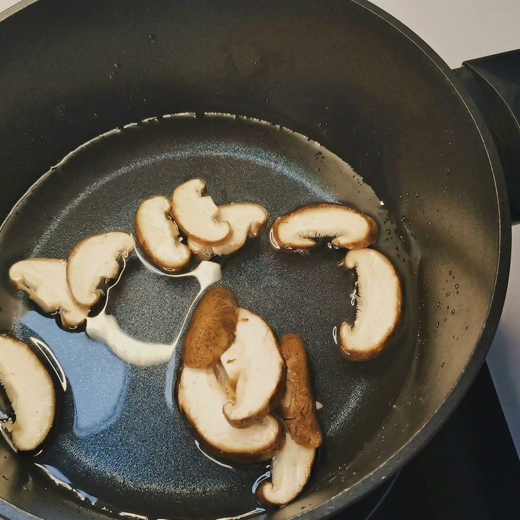Una pentola di acqua bollente con aggiunta di funghi affettati, germogli di soia e mais.