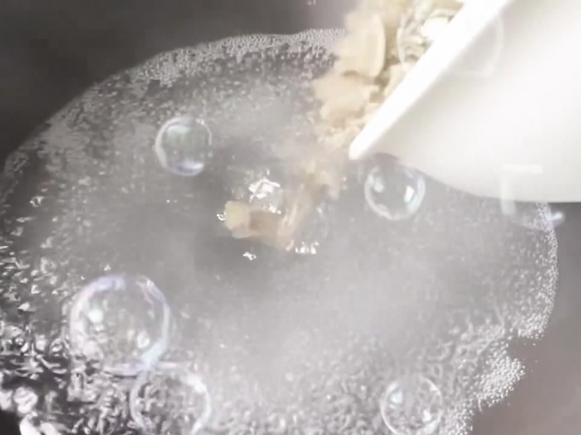 Vongole versate in una pentola di acqua bollente con aromi.