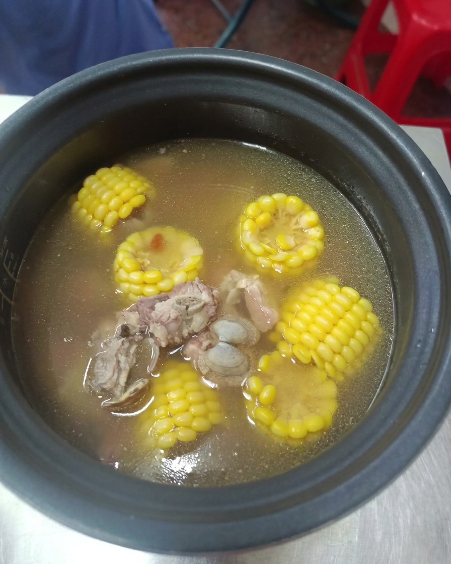 Una pentola a pressione aperta in sicurezza che rivela un brodo limpido caldo con costine di maiale tenere e mais giallo brillante.