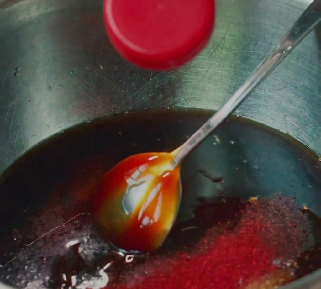 Carne di maiale macinata mescolata con vari condimenti liquidi in una ciotola di acciaio inox.