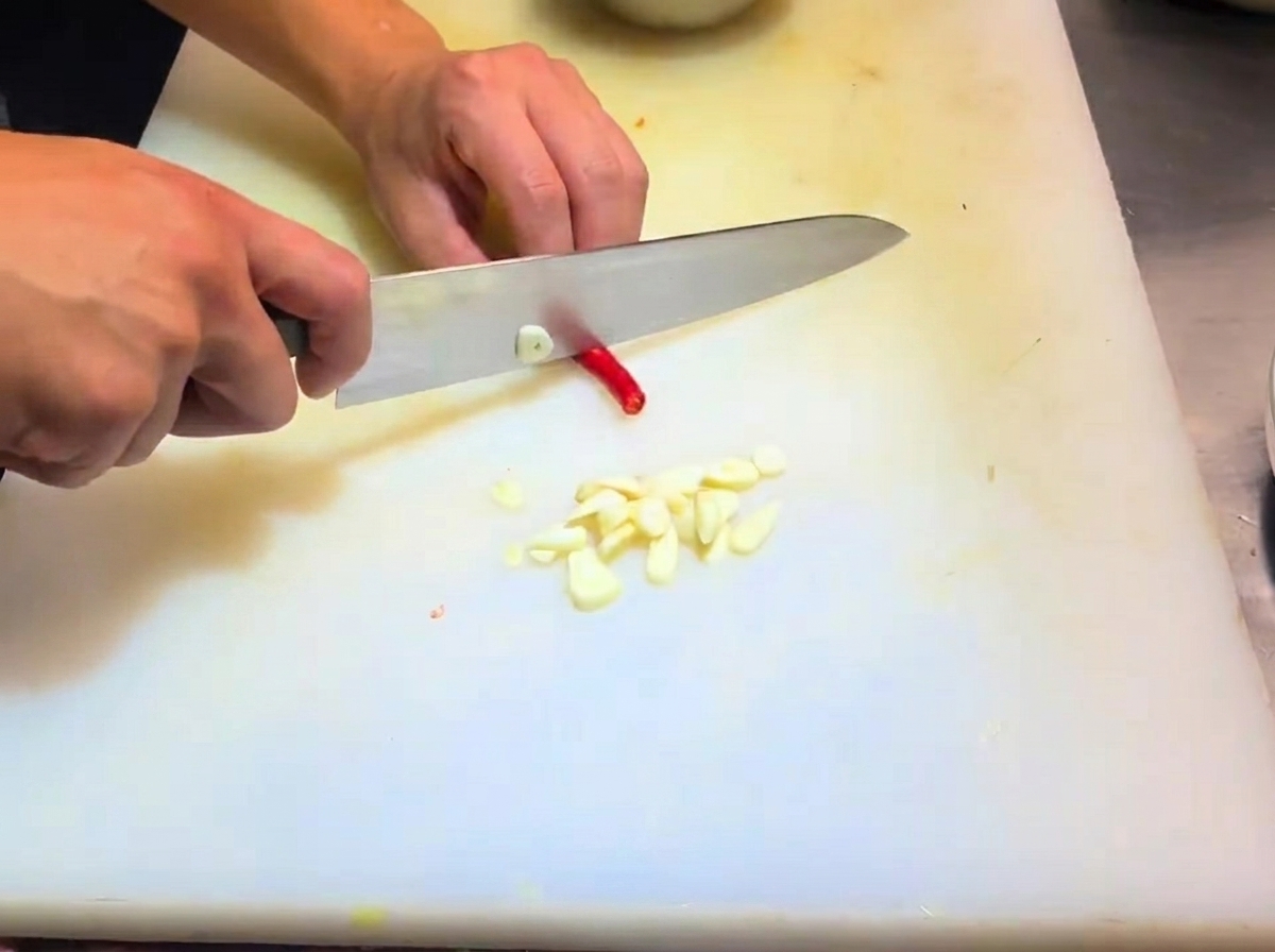 Scalogni affettati e pezzi di peperoncino preparati su un tagliere.