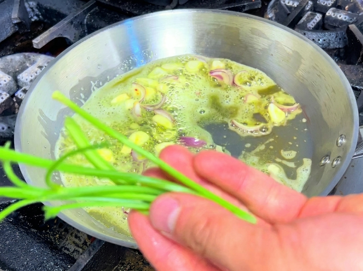 Gambi di prezzemolo che vengono saltati insieme ad aglio e scalogni in una padella di burro.