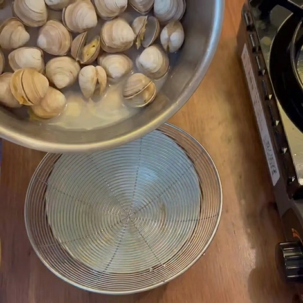 Il brodo liquido filtrato dalle vongole cotte in una ciotola sottostante.