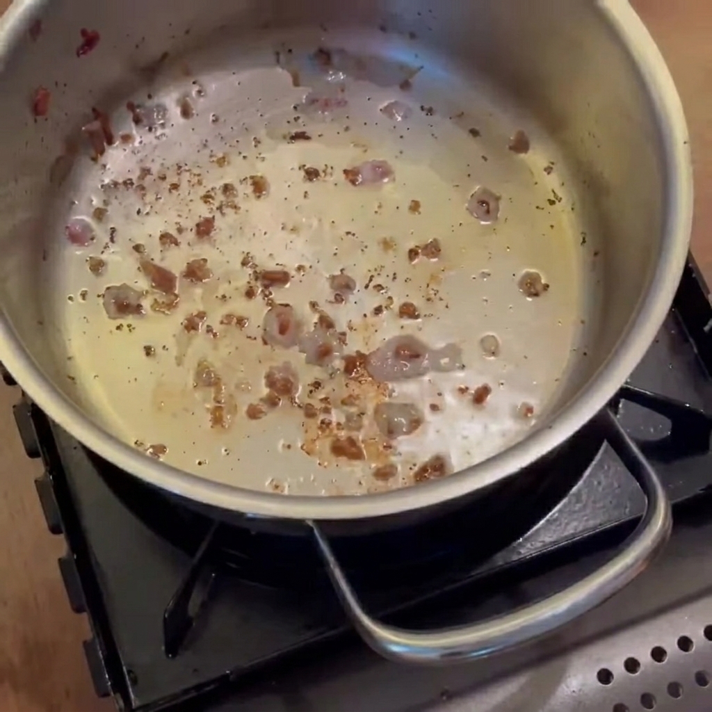 Cipolle, carote e patate che soffriggono nella pentola con il grasso di pancetta fino a diventare traslucide.