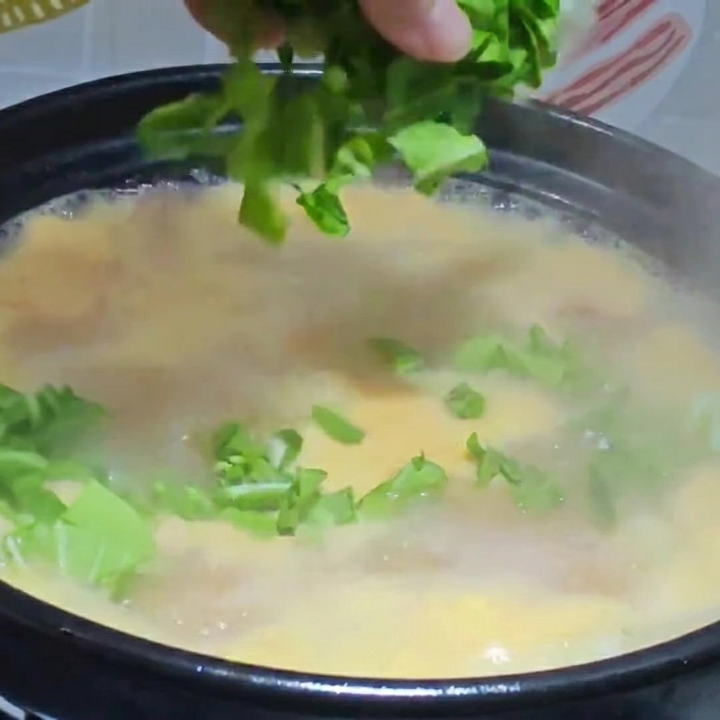 Verdure tritate e pollo sfilacciato aggiunti in un tegame di zuppa di gnocchetti bollente.