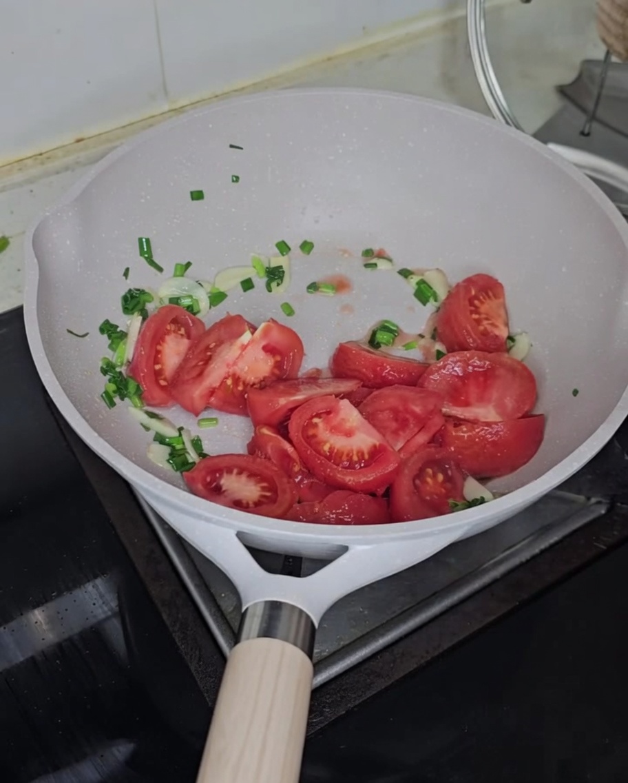 Pomodori freschi a cubetti aggiunti in padella con il soffritto.