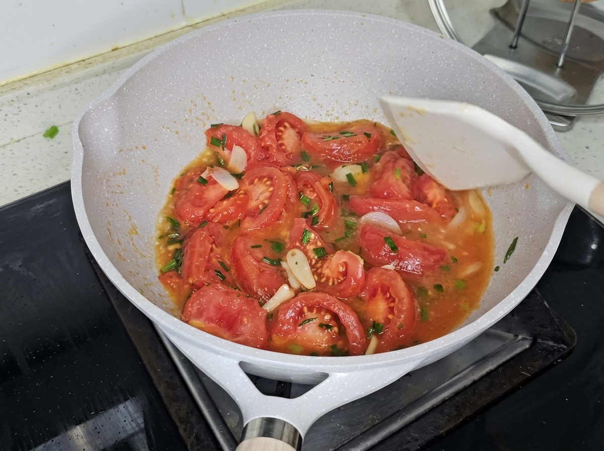 Acqua bollente versata in padella sopra i pomodori saltati.