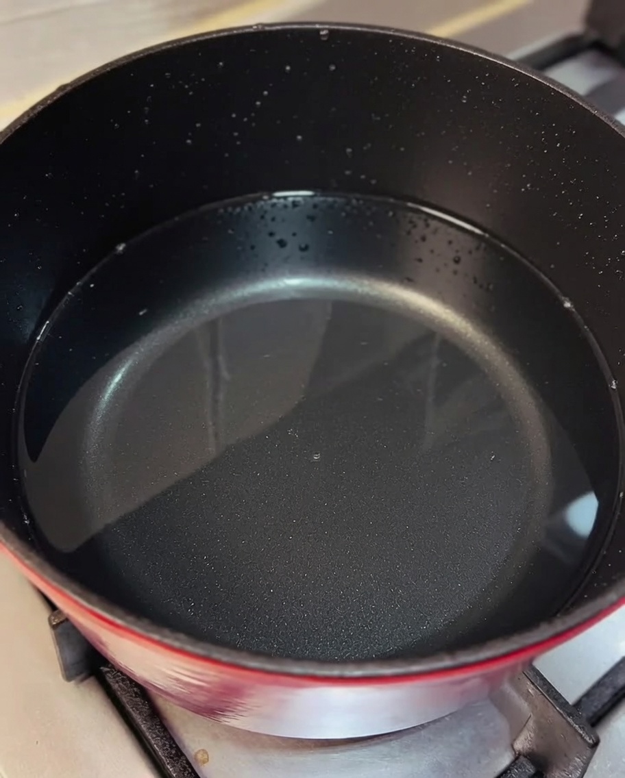 Pollo sfilacciato mescolato in una pentola di brodo bollente.