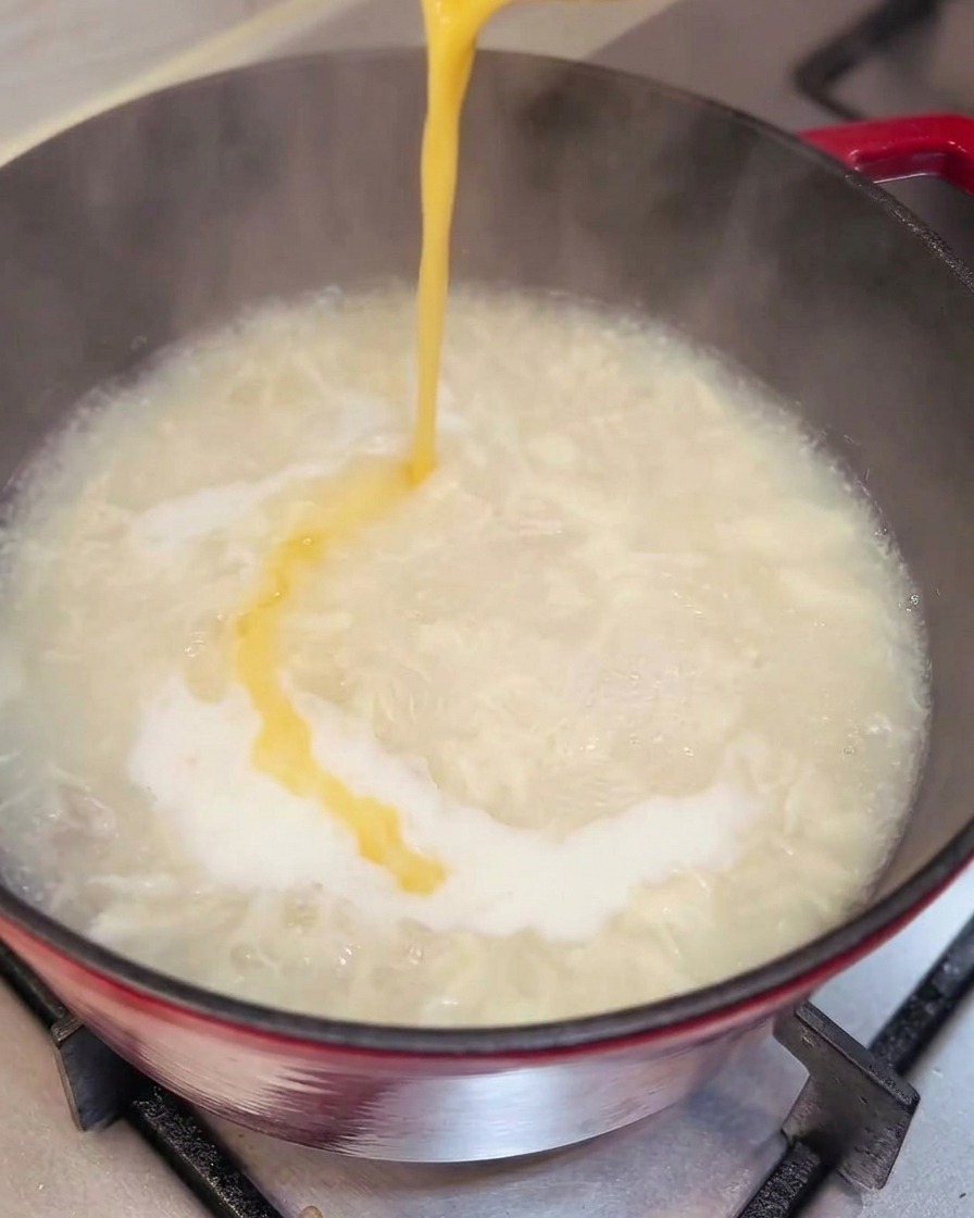 Uovo versato nella zuppa che forma dei nastri sottili.