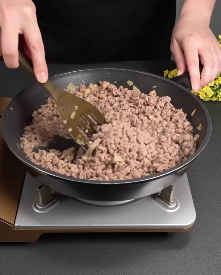 Carne macinata che rosola e si sgrana in padella insieme alle verdure.