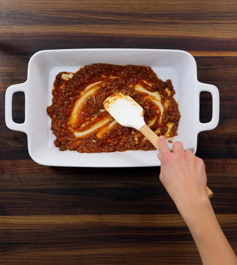 Una teglia da forno con i vari strati di ragù, sfoglie di pasta e besciamella pronti per la cottura.