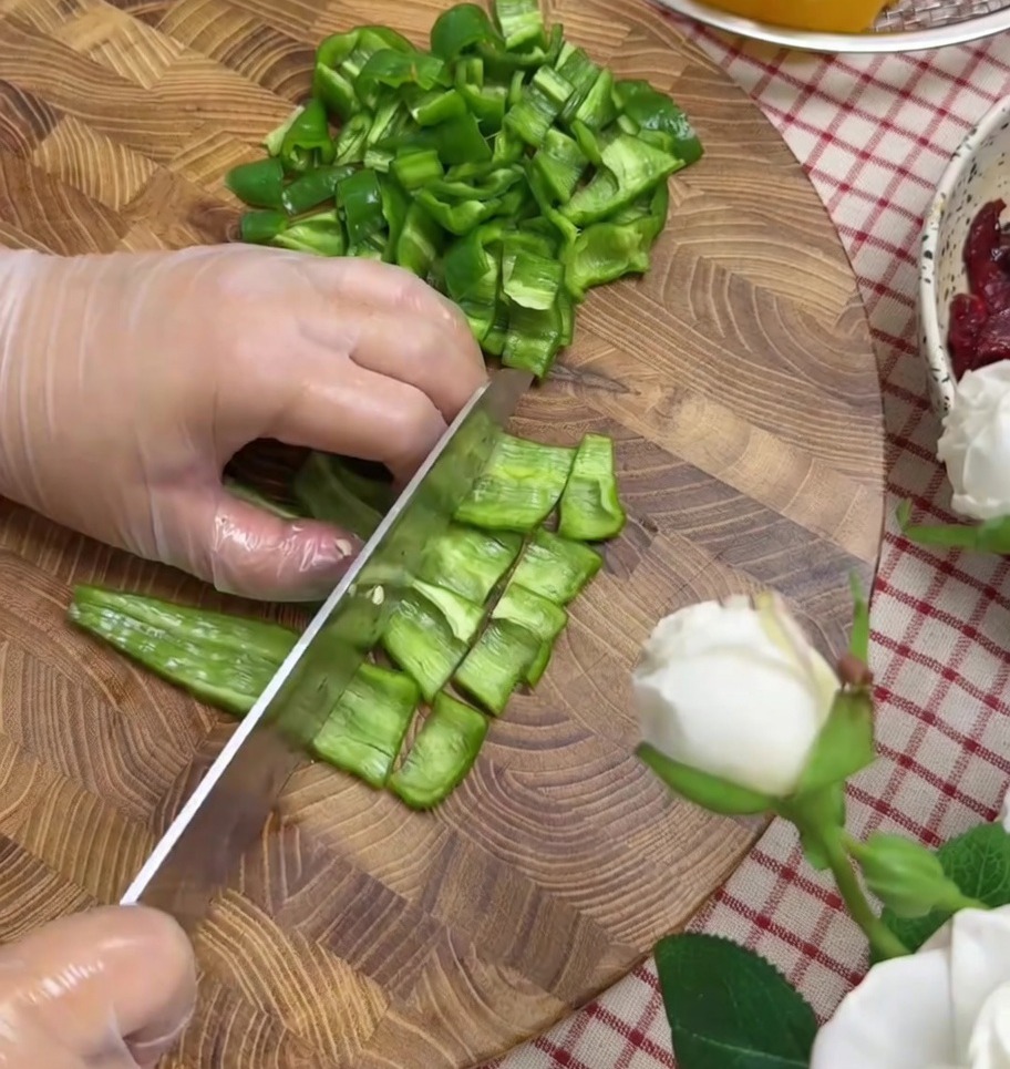 Peperoni e cipolla rossa tagliati a pezzetti su un tagliere.