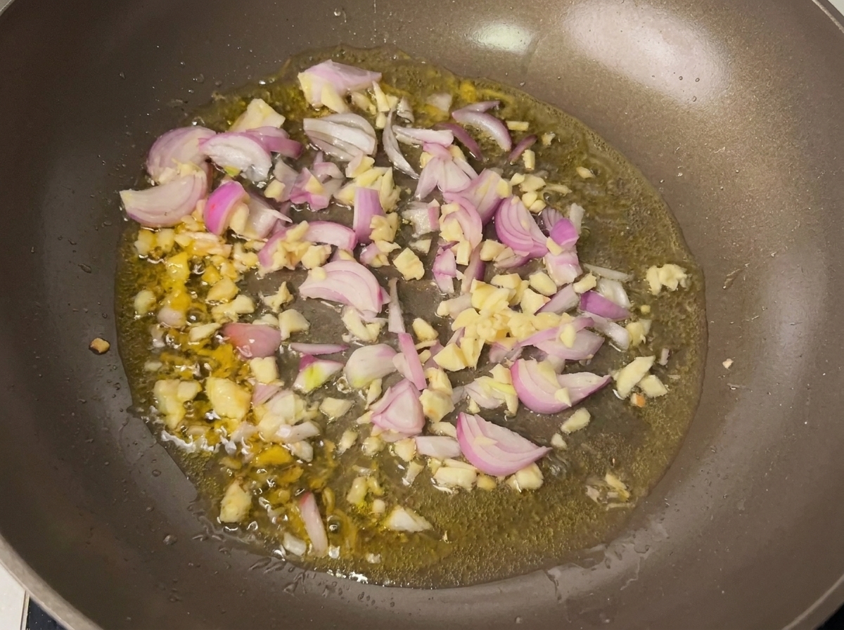 Aglio e scalogno che soffriggono in padella con olio caldo.