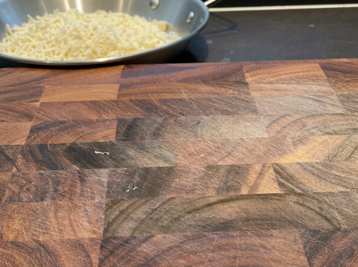 Fette di cheddar tagliate in strisce uniformi su un tagliere.