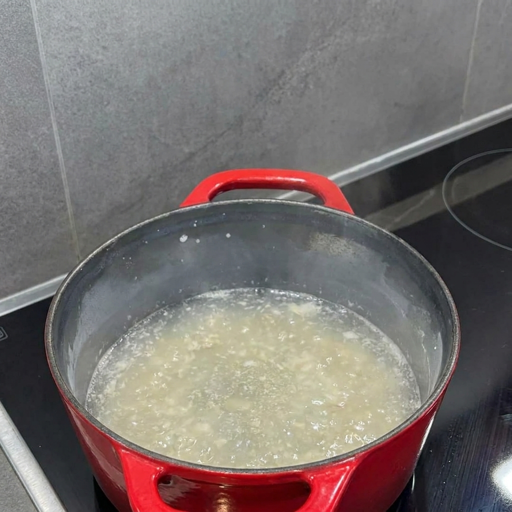 Latte versato nel roux allinterno della pentola e mescolato con una frusta fino a ottenere una crema.