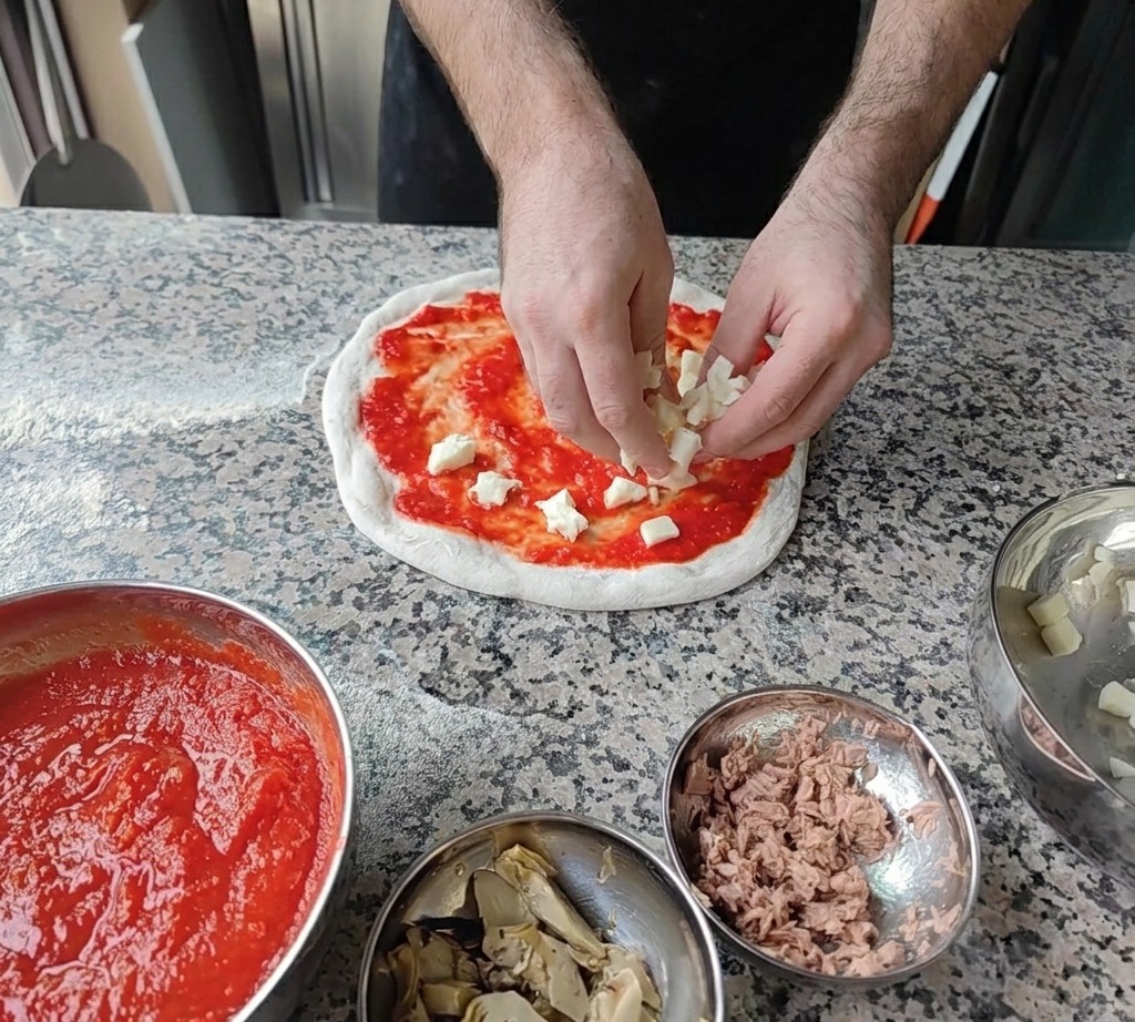 Cubetti di mozzarella fresca distribuiti sulla base di pomodoro.