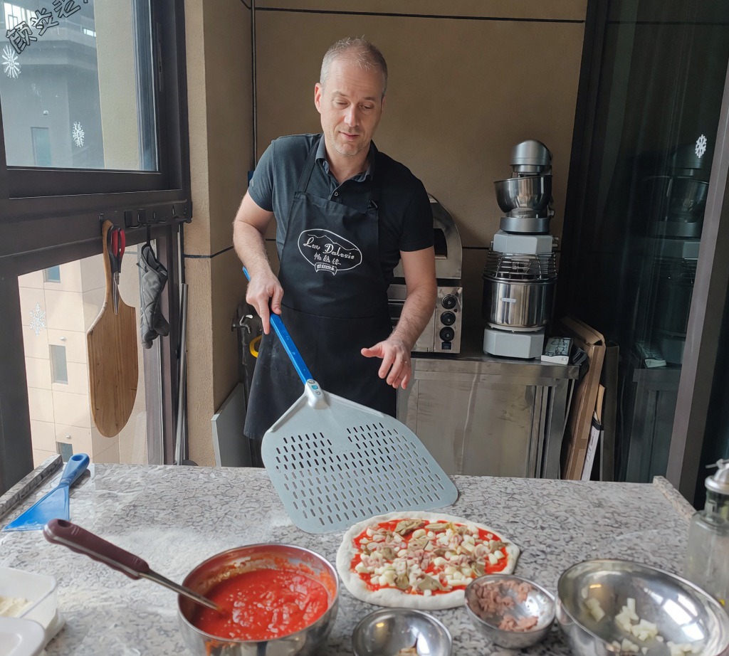 Una pala in metallo che scivola sotto la pizza assemblata cruda prima dellinfornata.