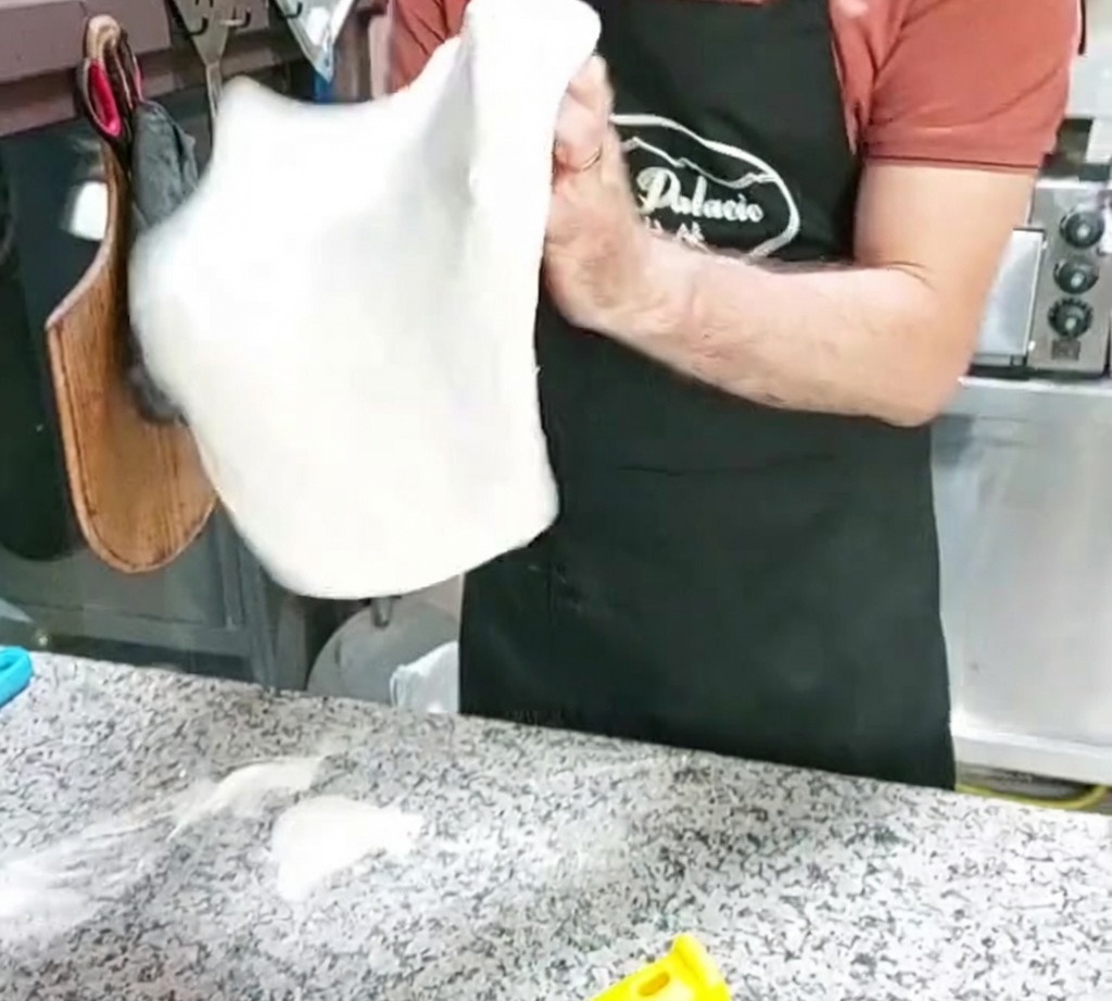 Una base di impasto per pizza che viene allargata facendola roteare nellaria.