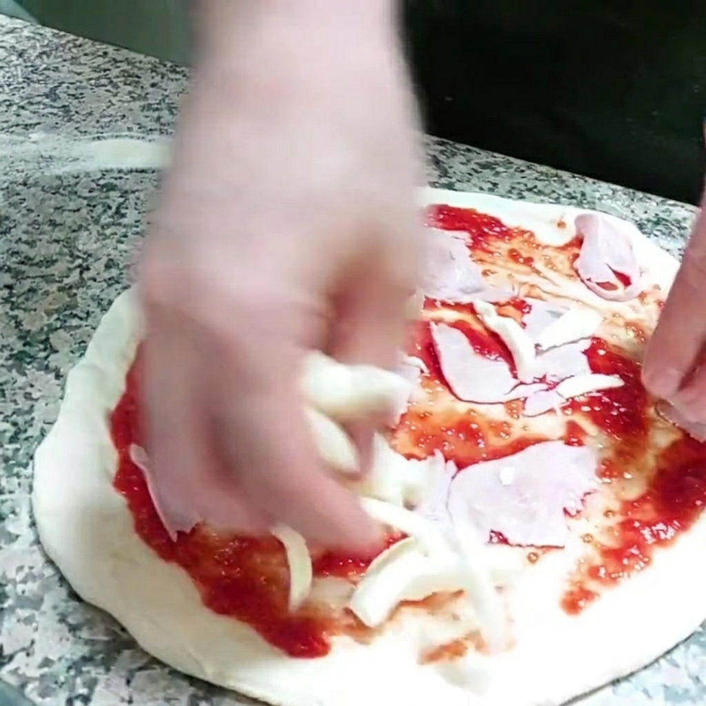 Pezzetti di mozzarella aggiunti sulla base della pizza.