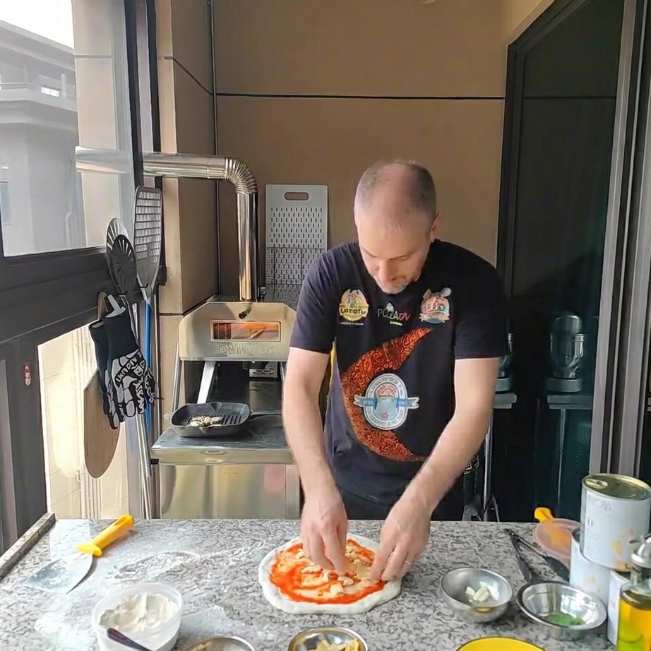 Mozzarella grattugiata che viene cosparsa sulla base della pizza condita con il pomodoro.