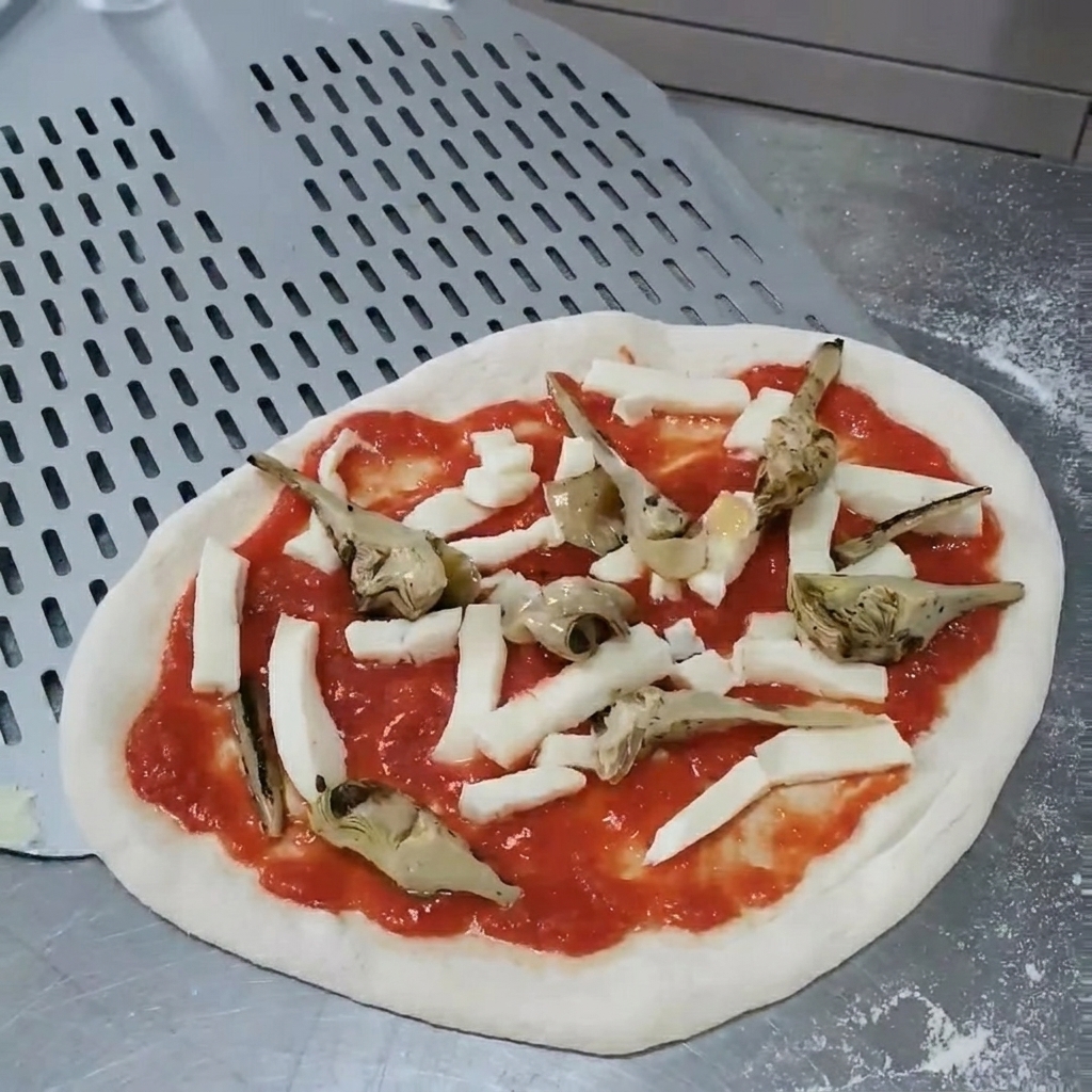 Mani che regolano la posizione dei carciofi sulla pizza cruda per garantire una copertura uniforme.