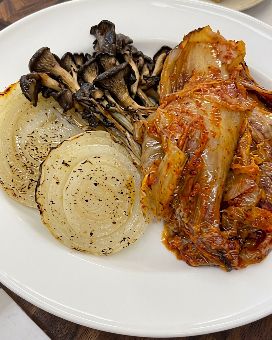 Semi di sesamo cosparsi sopra le verdure arrosto e il kimchi su un piatto.
