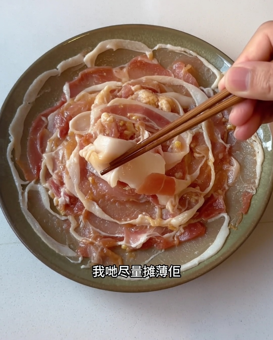 Fette di pancia di maiale marinata disposte con cura in un singolo strato su un piatto utilizzando delle bacchette.