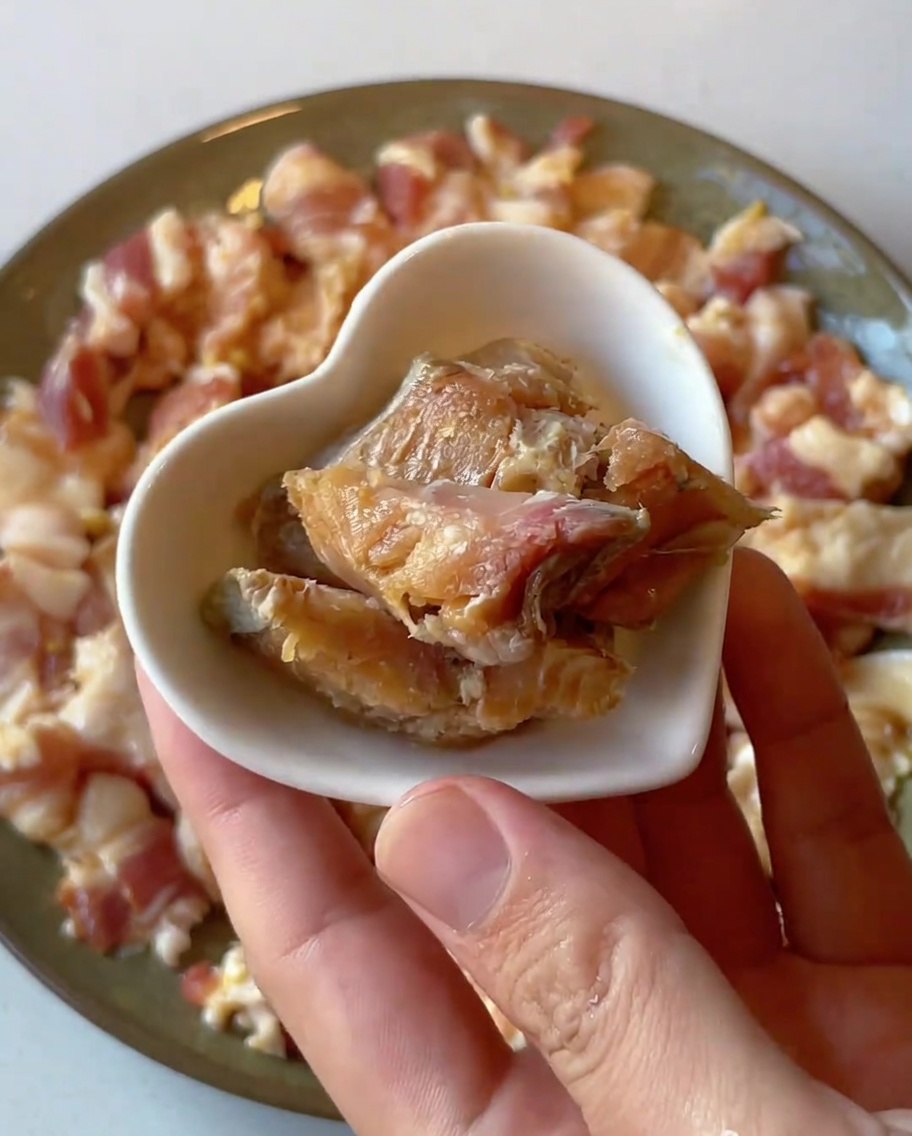 Primo piano di piccoli pezzi di pesce salato posizionati su un piatto di maiale crudo marinato.