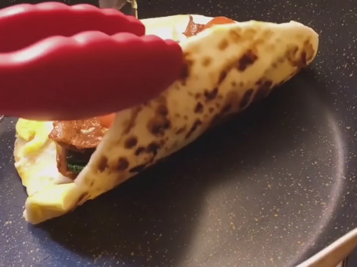 Un wrap di pane piatto allo scalogno appena preparato che viene arrotolato strettamente su una superficie piana.