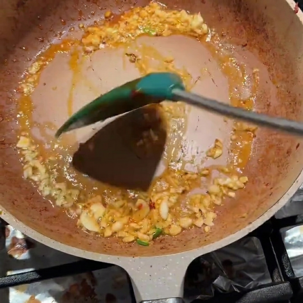 Aglio tritato e pasta di fagioli Pixian mescolati insieme in una padella.