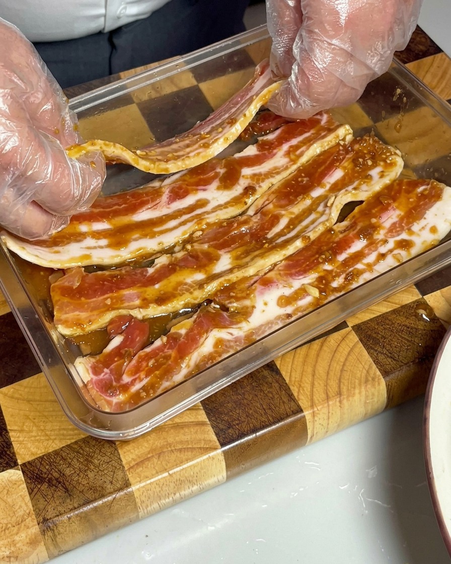 Strisce di pancetta marinata disposte in un contenitore trasparente, completamente sommerse nella salsa al miso.