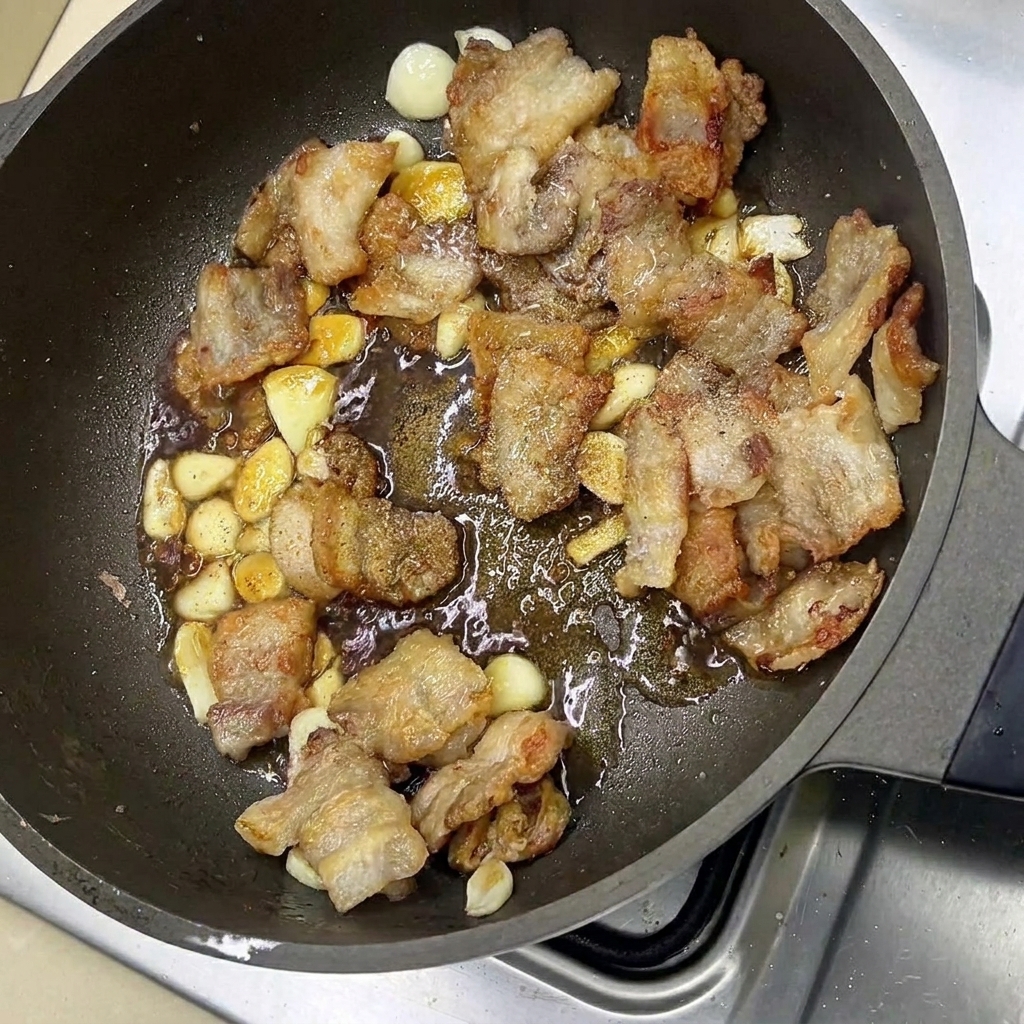 Pancetta glassata e spicchi daglio saltati in padella con le salse.