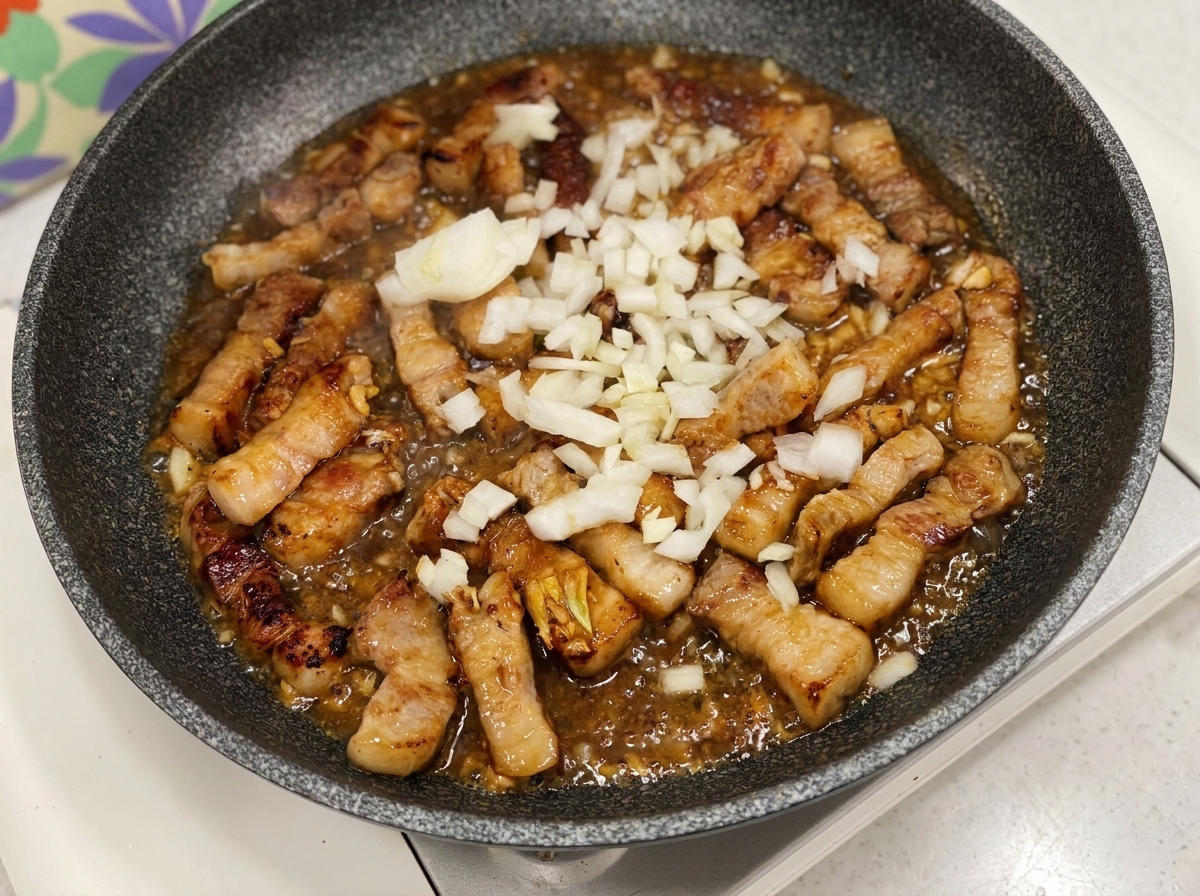 Cipolle bianche tritate aggiunte nella padella con la carne e la salsa sfrigolante.