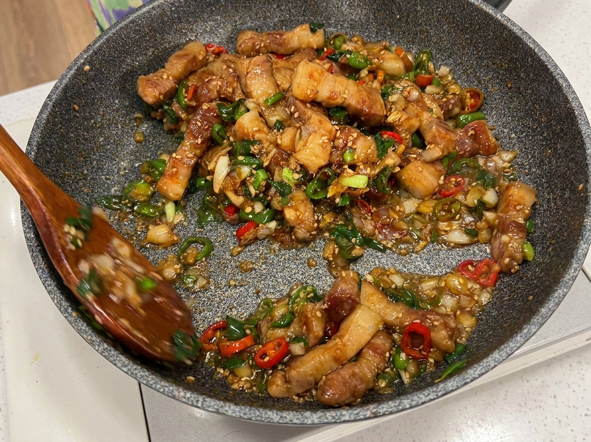 Pancetta, peperoncini e cipollotti mescolati in padella con due cucchiai di legno.