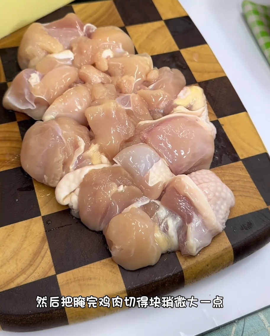 Pezzi uniformi di coscia di pollo cruda su un tagliere di legno.