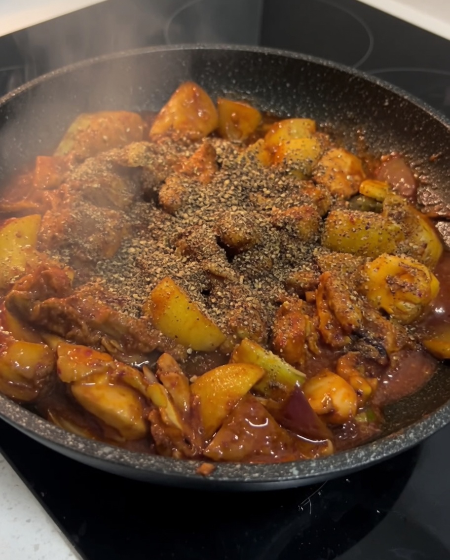 Finitura del pollo piccante coreano condito con polvere di perilla nella padella.