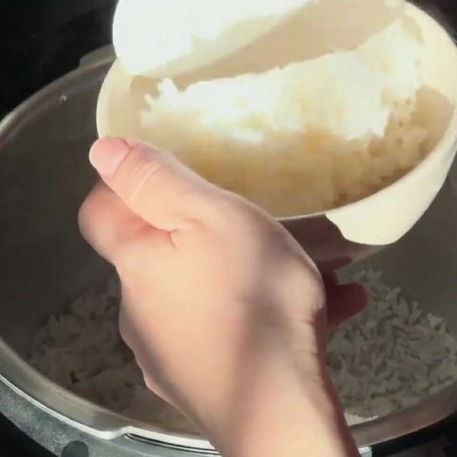 Riso bianco al vapore versato in una ciotola chiara con una spatola per riso.