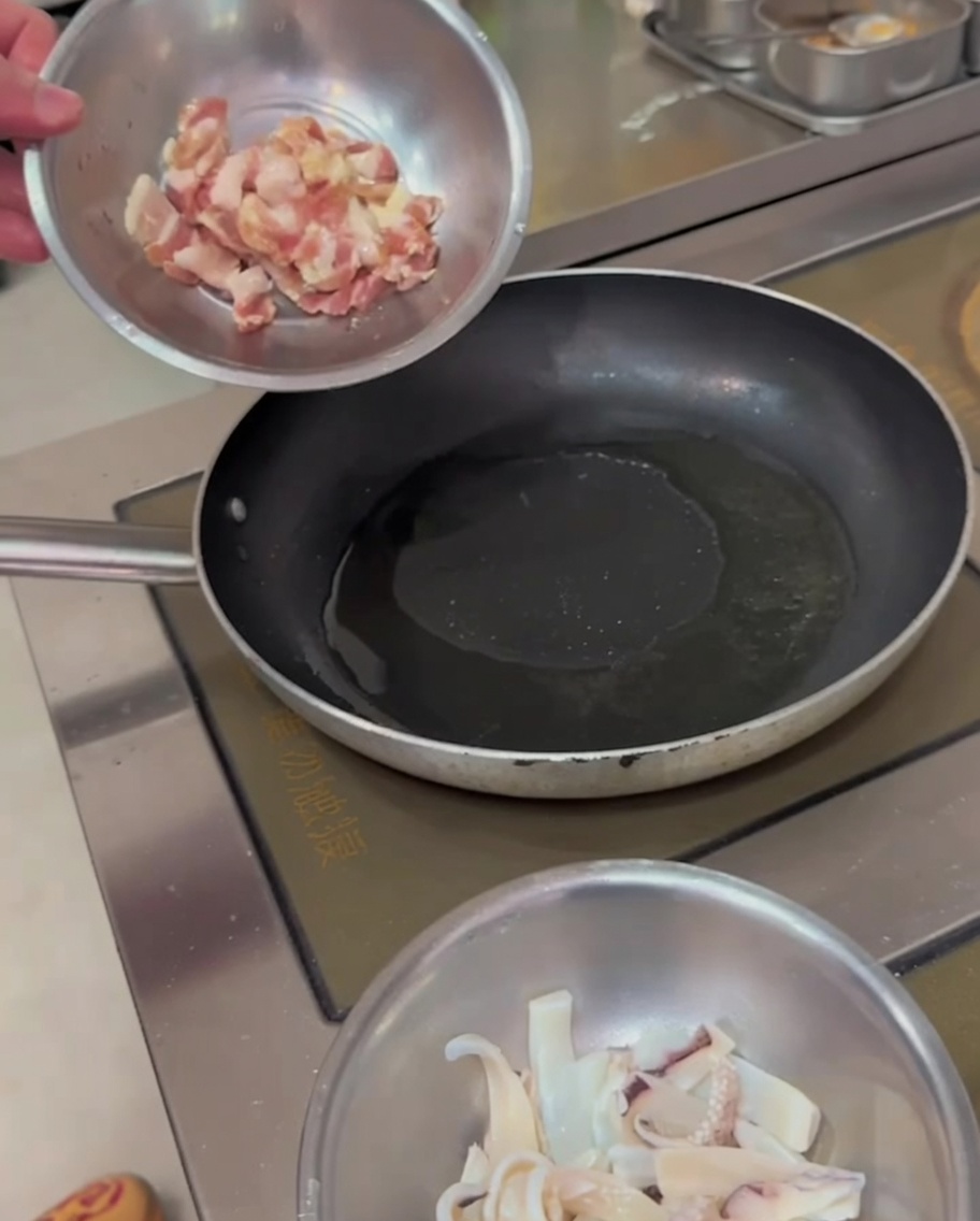 Strisce di pancetta che sfrigolano in una padella calda, mostrando bordi dorati.