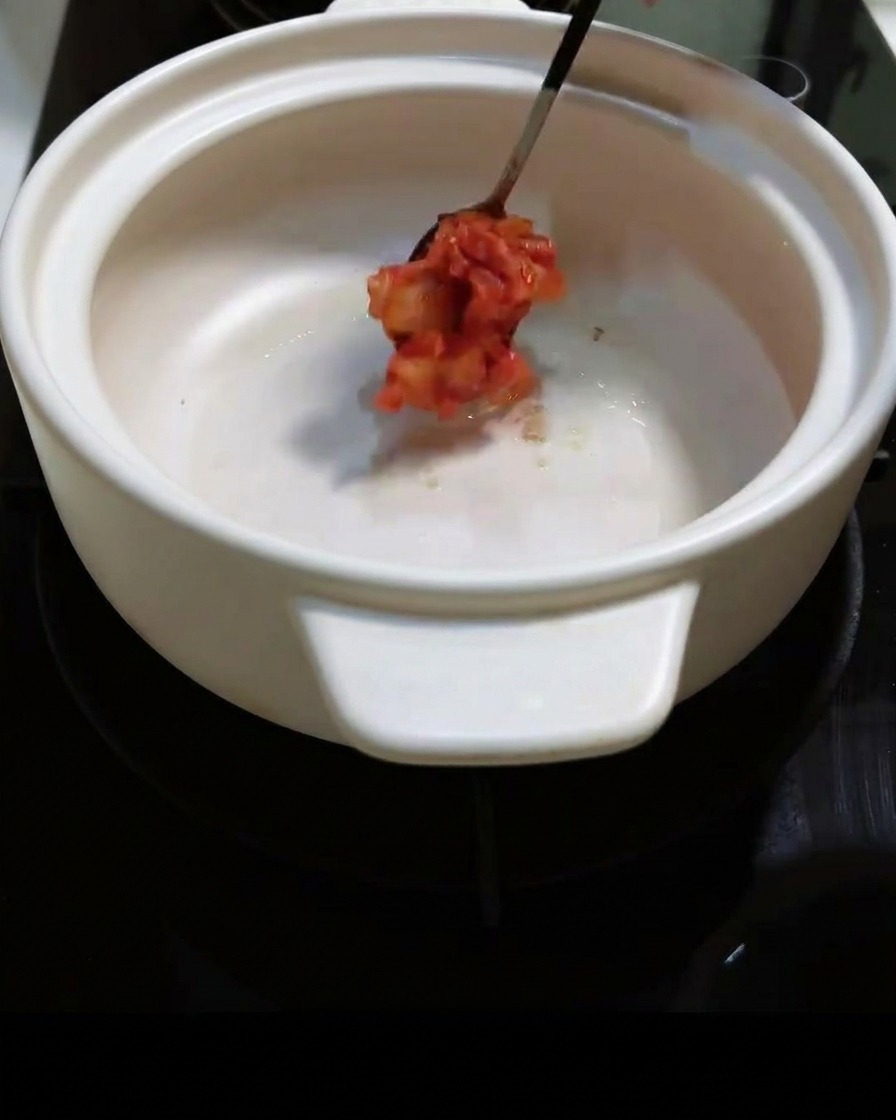 Il kimchi piccante tritato viene aggiunto alla pentola e mescolato.