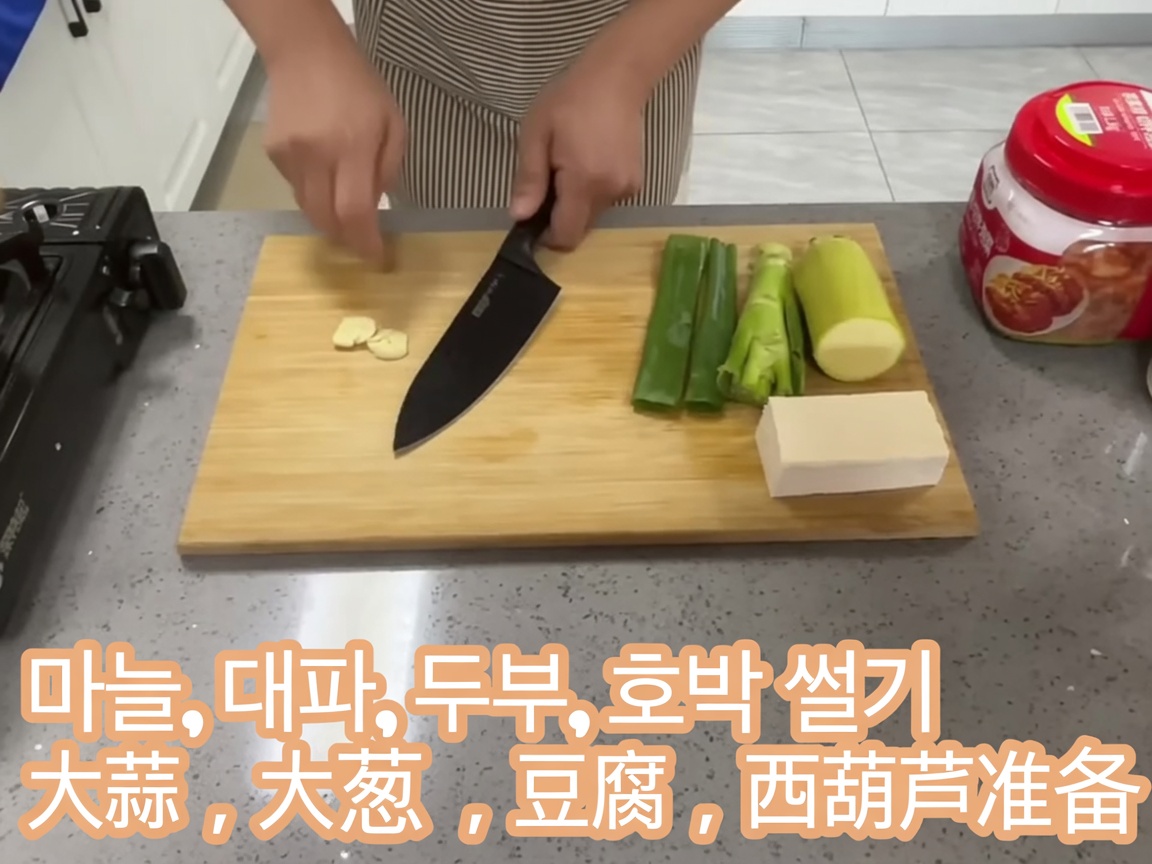 Spicchi daglio crudi affettati sottilmente disposti su un tagliere di legno.
