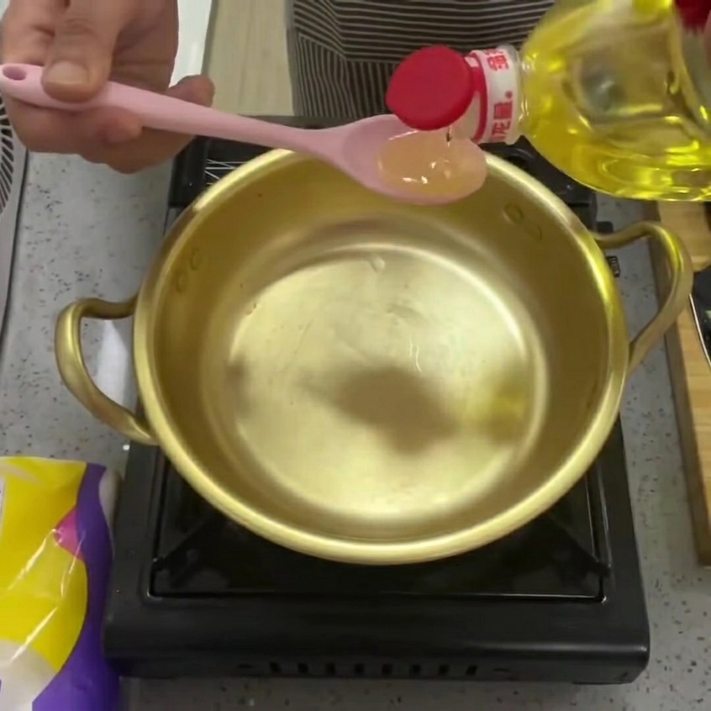 Olio da cucina versato in una lucente pentola di ottone.